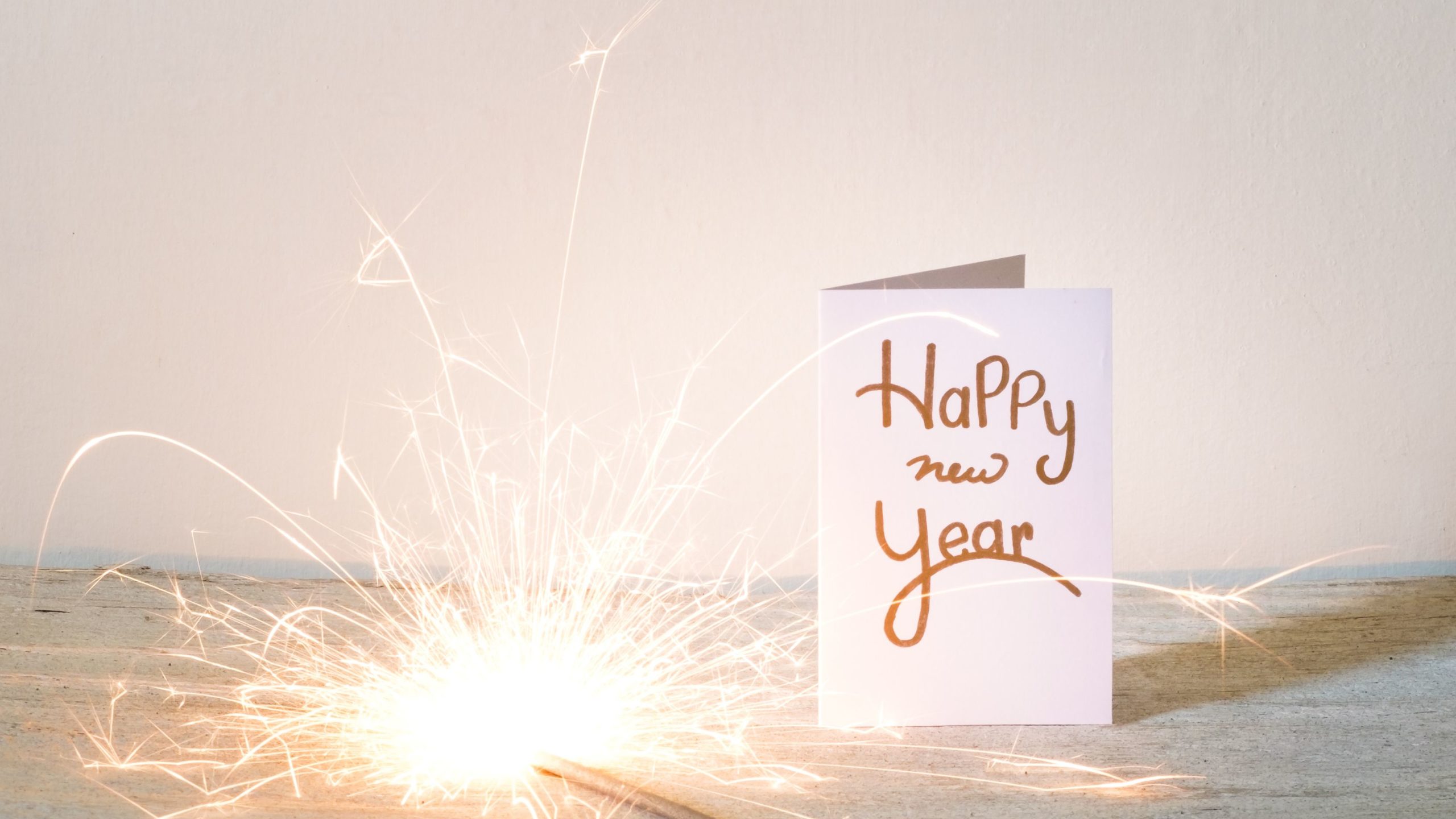 new-year-card-with-lit-sparkler-on-table-against-wall-688969401-5bd668bc46e0fb0026718605